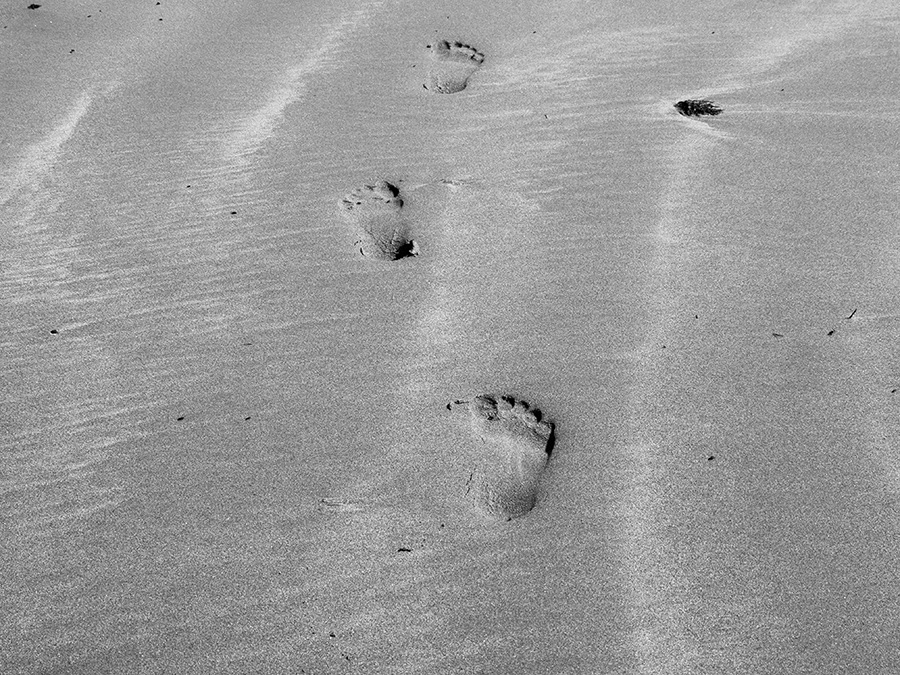 Black and White Photo of Footprints in Wet Beach Sand.